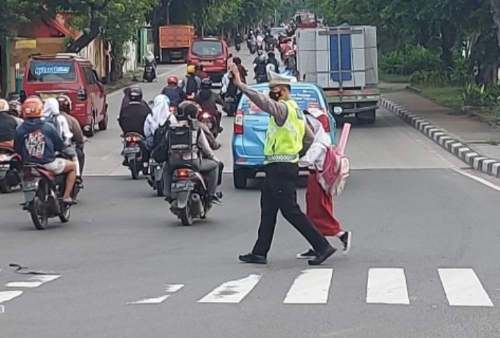 Satuan Lalulintas Polres Metro Jakarta Barat Bantu Sebrangkan Anak Sekolah Dasar Yang Berangkat Belajar